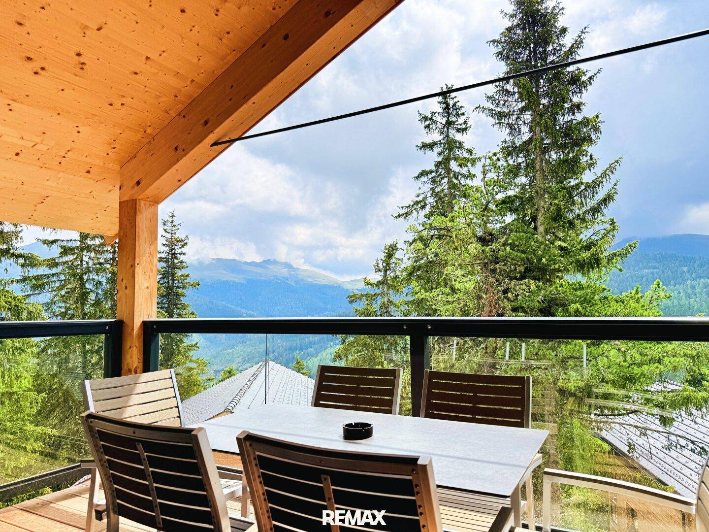 Geräumiger Balkon mit Esstisch, Stühlen und atemberaubendem Bergblick.