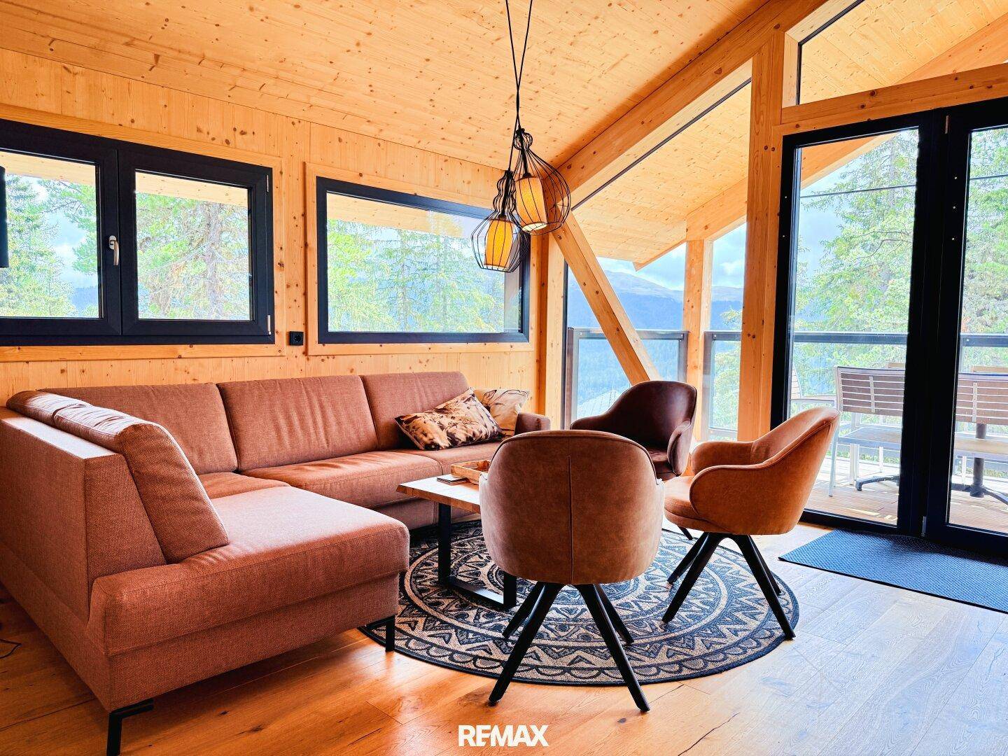Heller Wohnbereich mit bequemer Couch, Holzboden und großen Fenstern mit Bergblick.