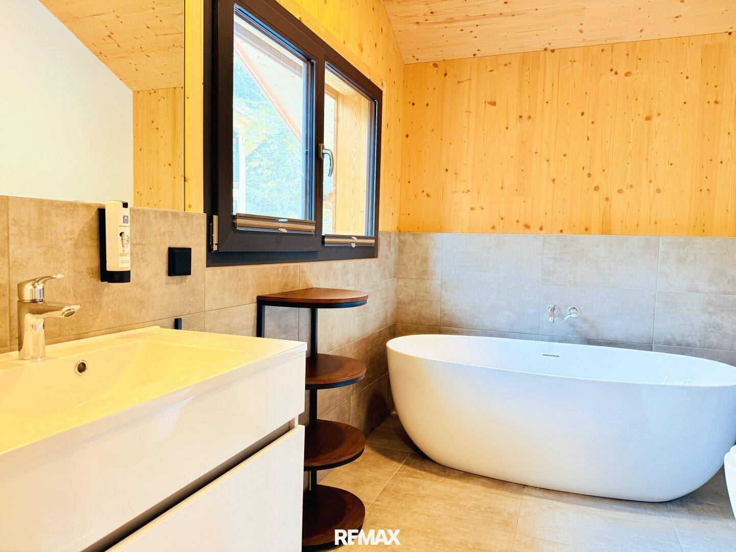 Modernes Badezimmer mit freistehender Badewanne, Fliesenboden und Holzvertäfelung.