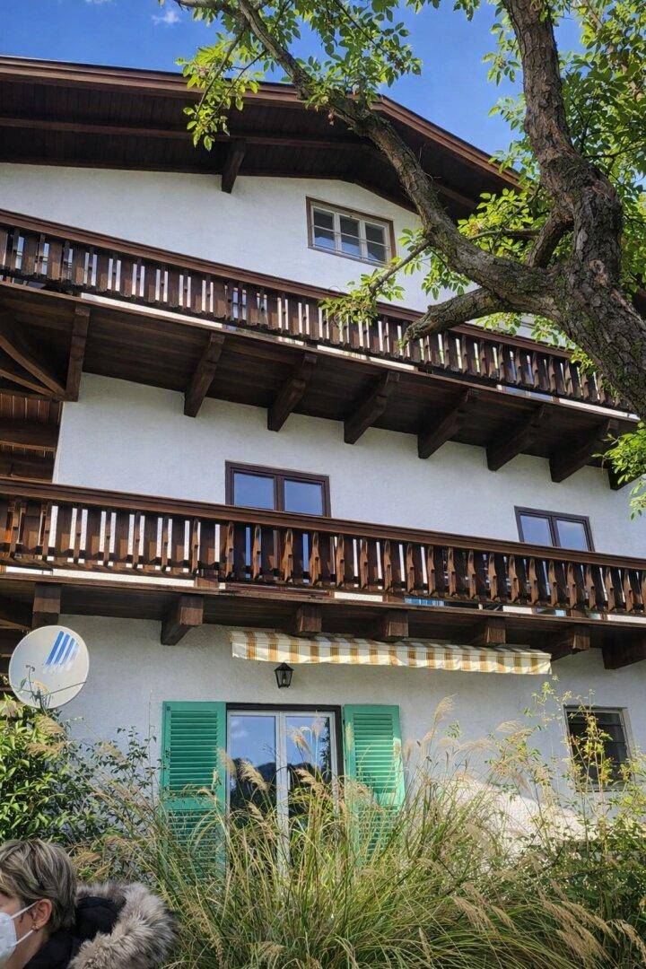 Fassade eines Hauses mit mehreren Holzbalkonen und grünen Fensterläden.