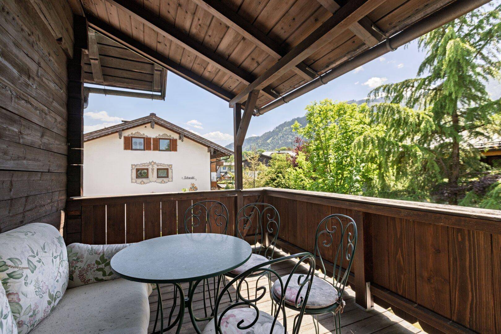 Gemütlicher Holzbalkon mit Sitzgelegenheiten und weitem Blick auf die Bergwelt.
