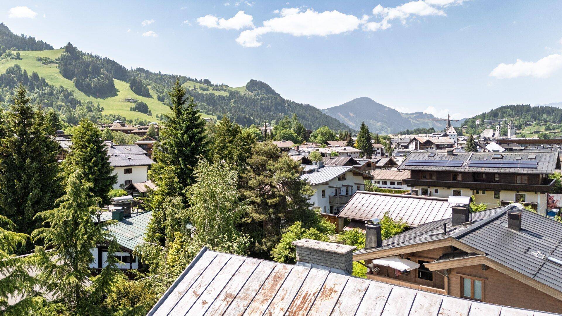 Weitläufiger Panoramablick über die Dächer der Stadt und die umliegenden grünen Berge.