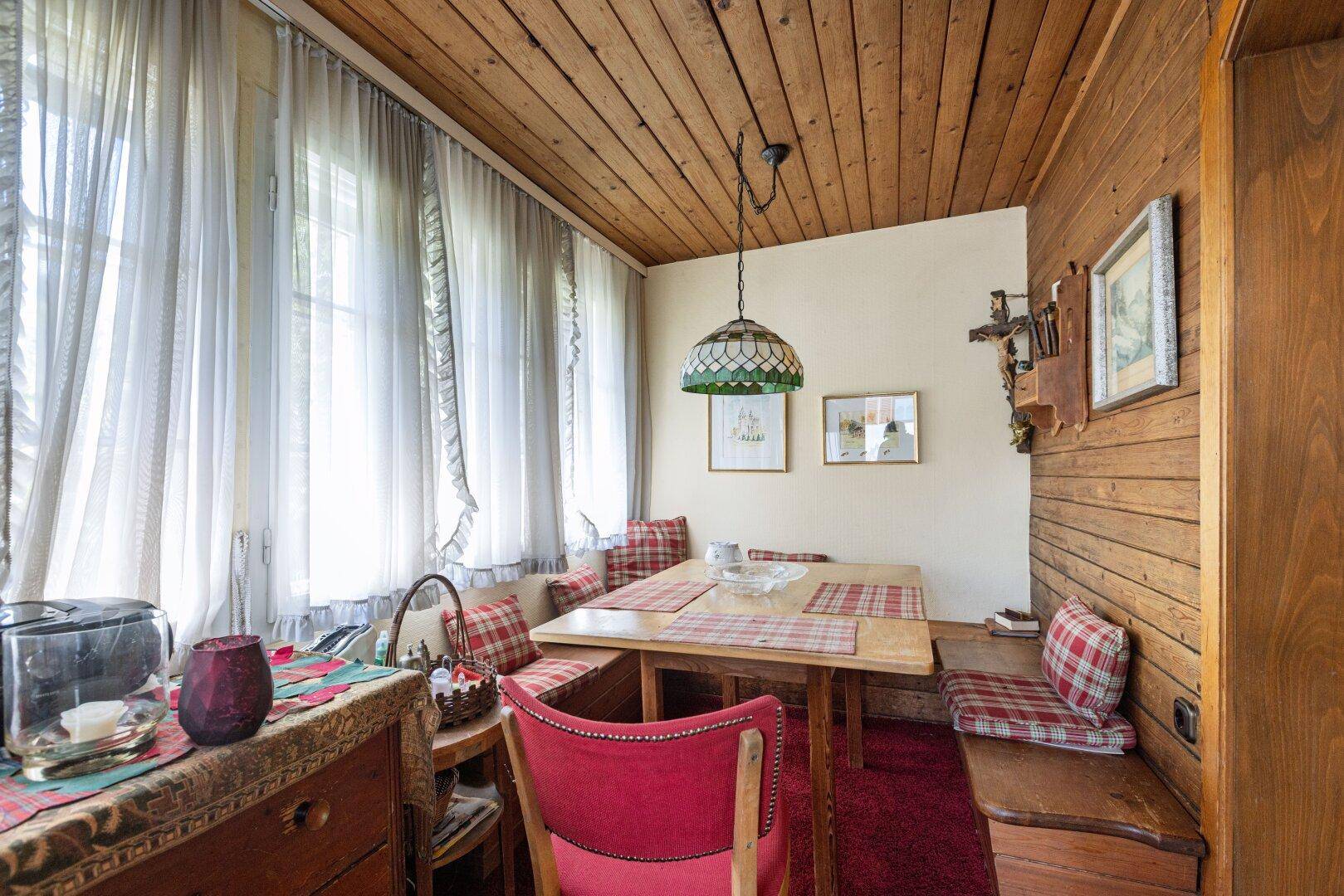 Rustikaler Essbereich im alpinen Stil mit Holzwänden, Holzbalkendecke und traditioneller Einrichtung.