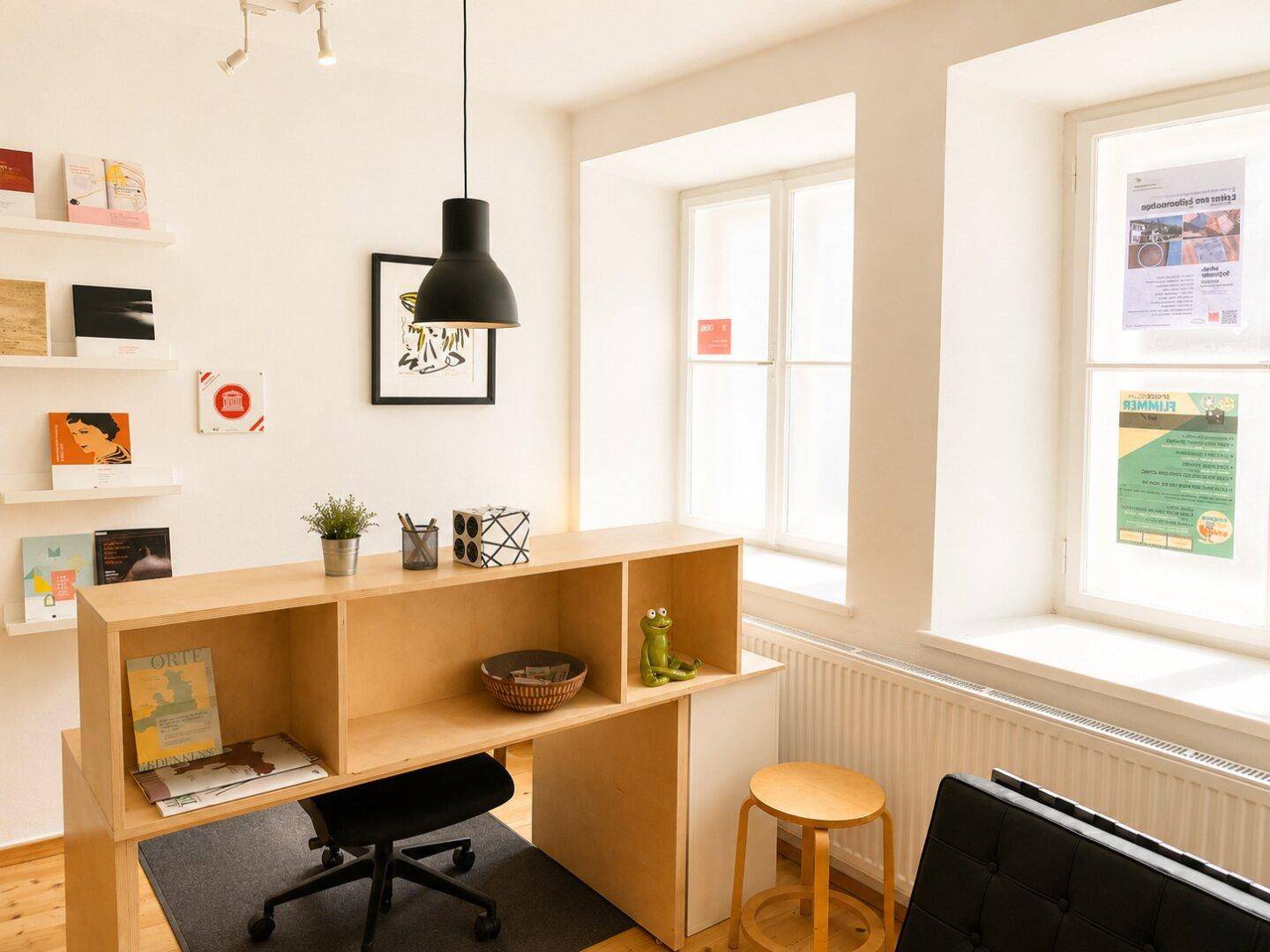 Helles Büro mit einem modernen Holzschreibtisch, Wandregalen und großen Fenstern, die viel Licht hereinlassen.