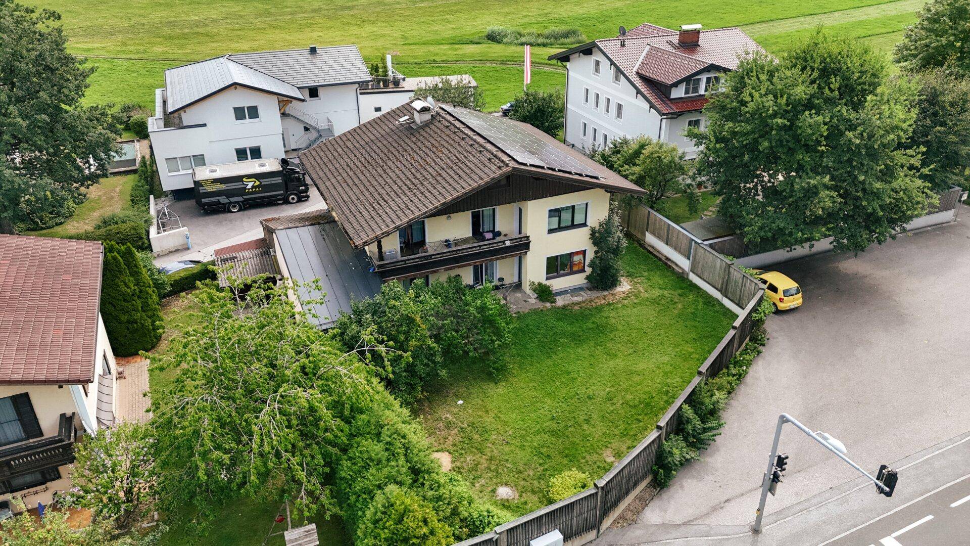 Luftaufnahme der Rückseite des Hauses mit Balkon, großem Rasen und weiten Feldern im ländlichen Hintergrund.