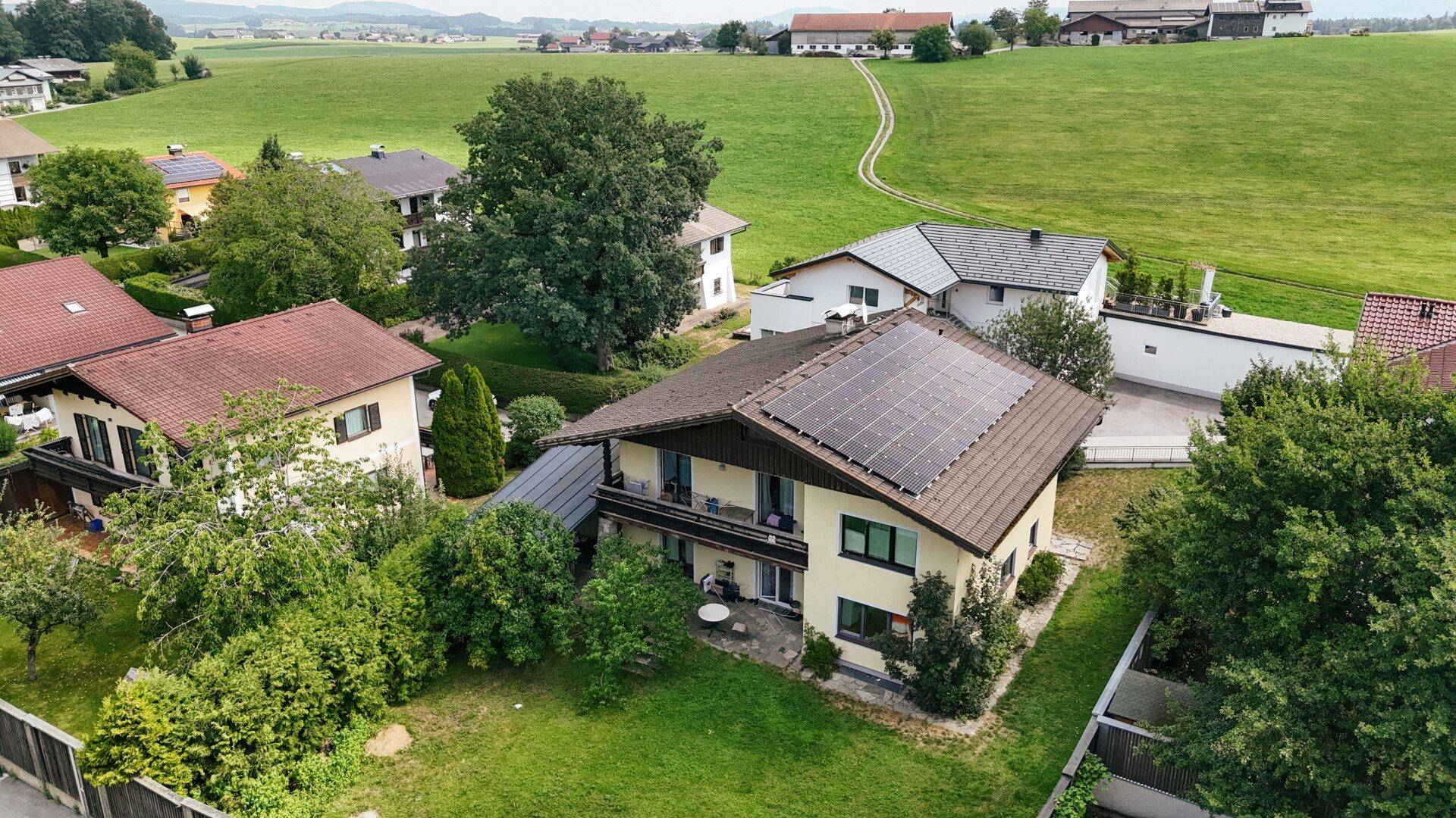 Luftaufnahme des Hauses mit Solaranlage, Balkon und weitläufigen grünen Feldern in der ländlichen Umgebung.