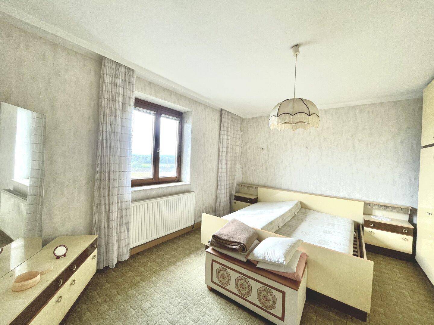 Gemütliches Schlafzimmer mit Doppelbett, Nachttischen und einem Fenster mit Blick ins Grüne.