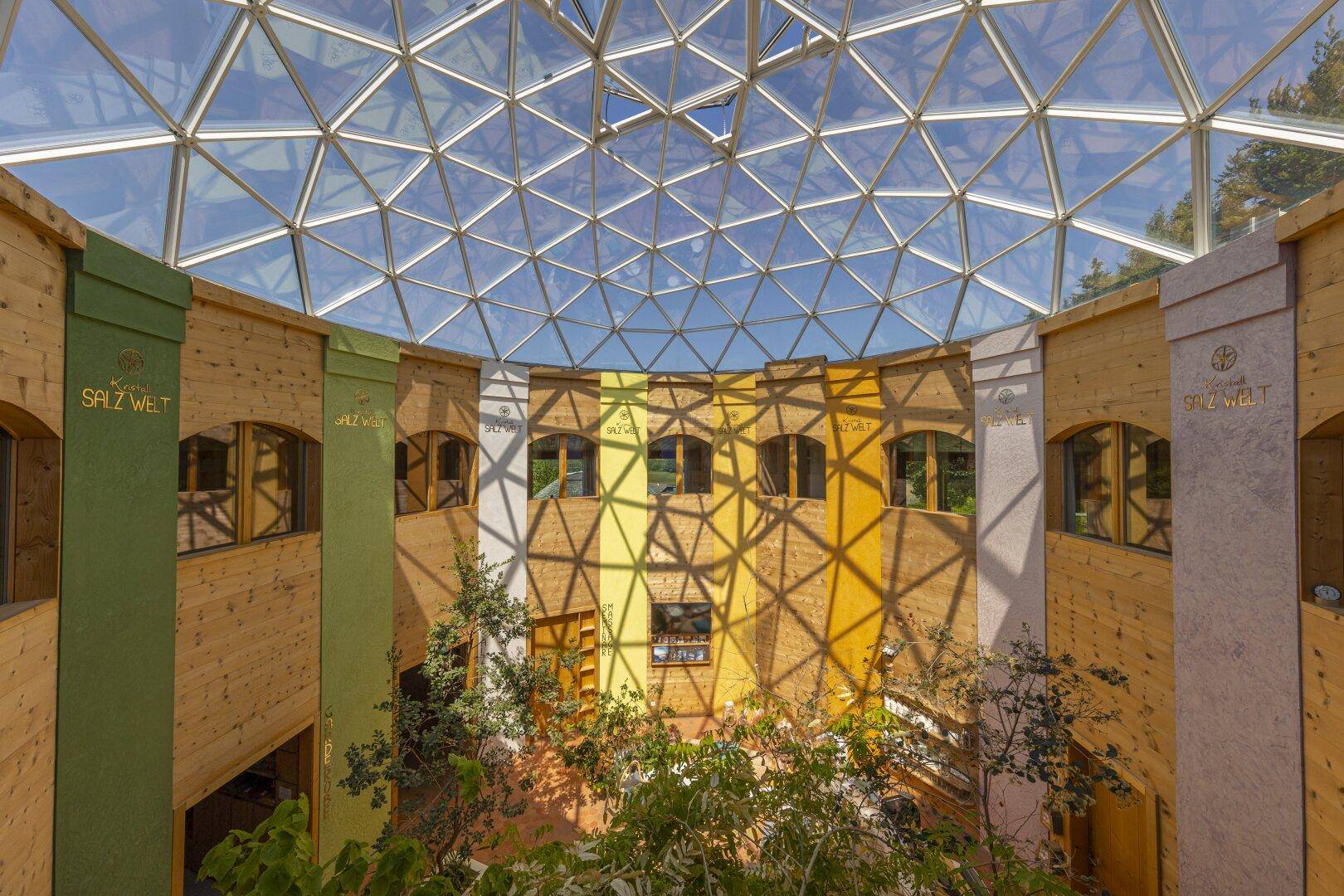 Lichtdurchflutetes Atrium mit beeindruckender Glaskuppel und farbigen Wänden.