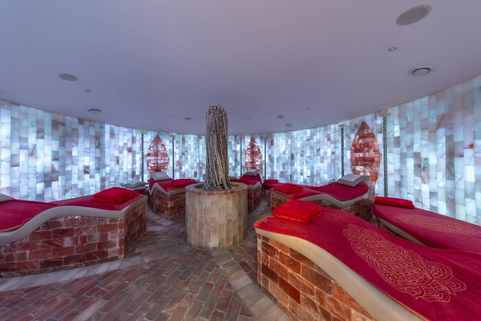 Entspannungsraum mit beleuchteten Salzwänden und bequemen Liegen für Wellness.