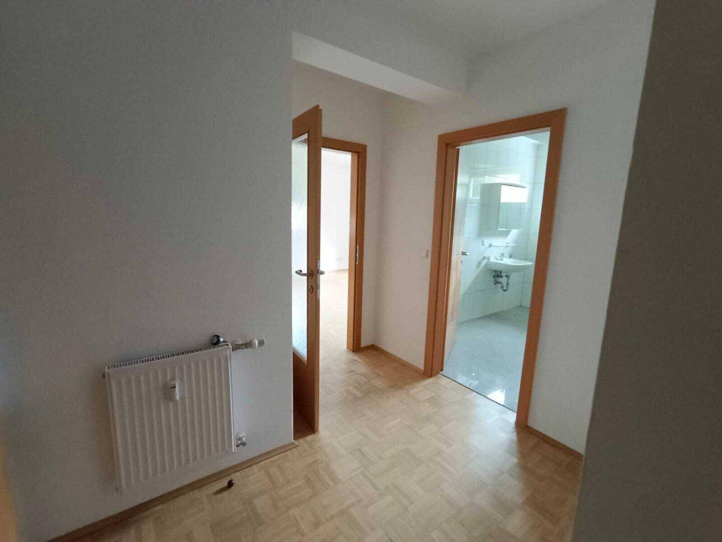 Flur mit Parkettboden und Zugang zu weiteren Räumen, inklusive Badezimmer.