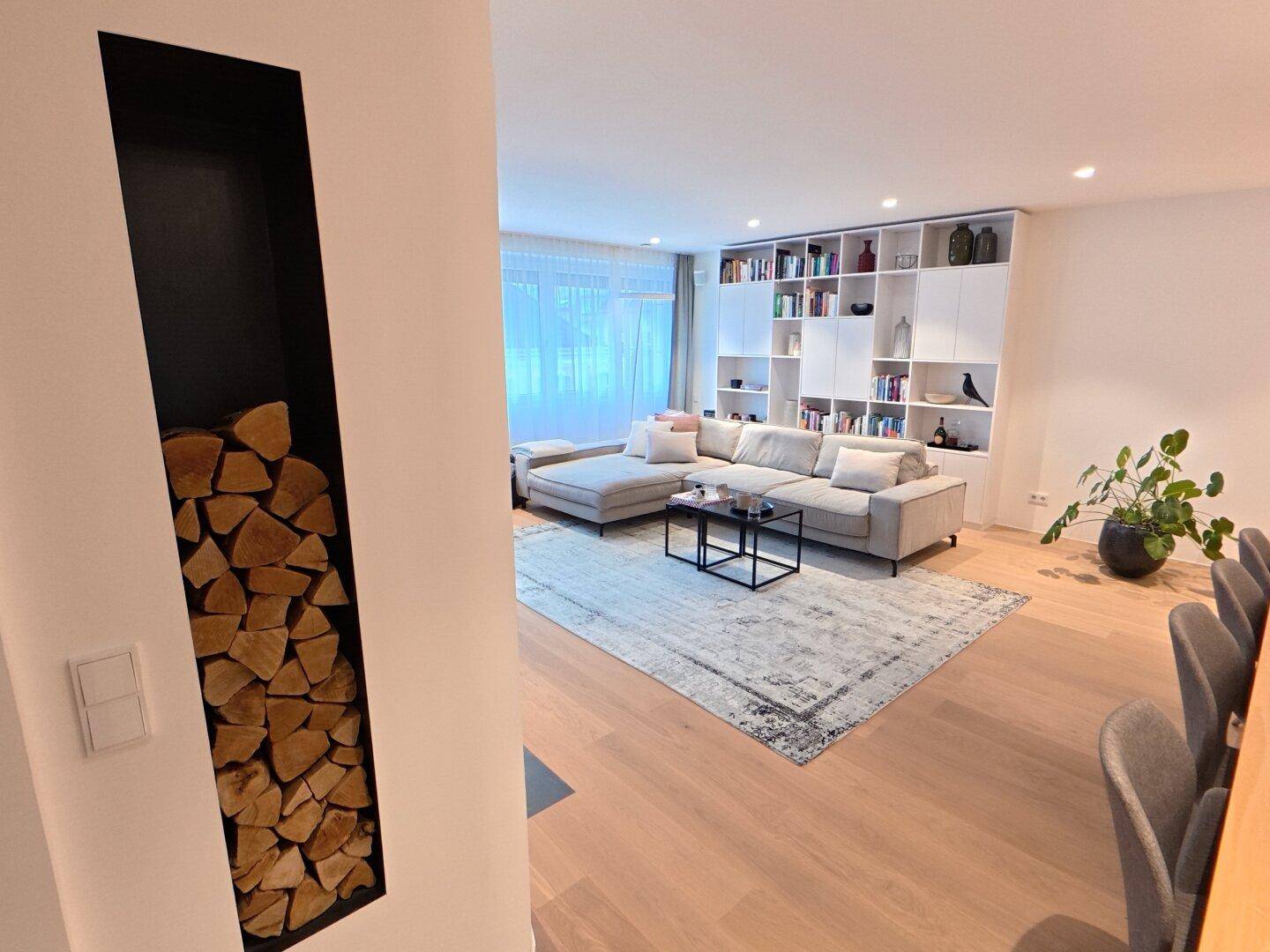 Gemütliches Wohnzimmer mit großem Sofa, Bücherregal und integriertem Holzlager für den Kamin.