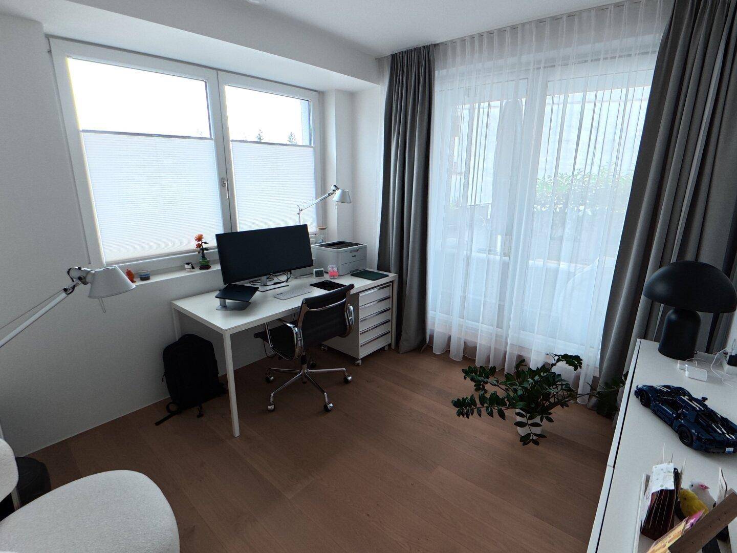 Helles Arbeitszimmer mit Schreibtisch, Bürostuhl und großen Fenstern für viel Tageslicht.