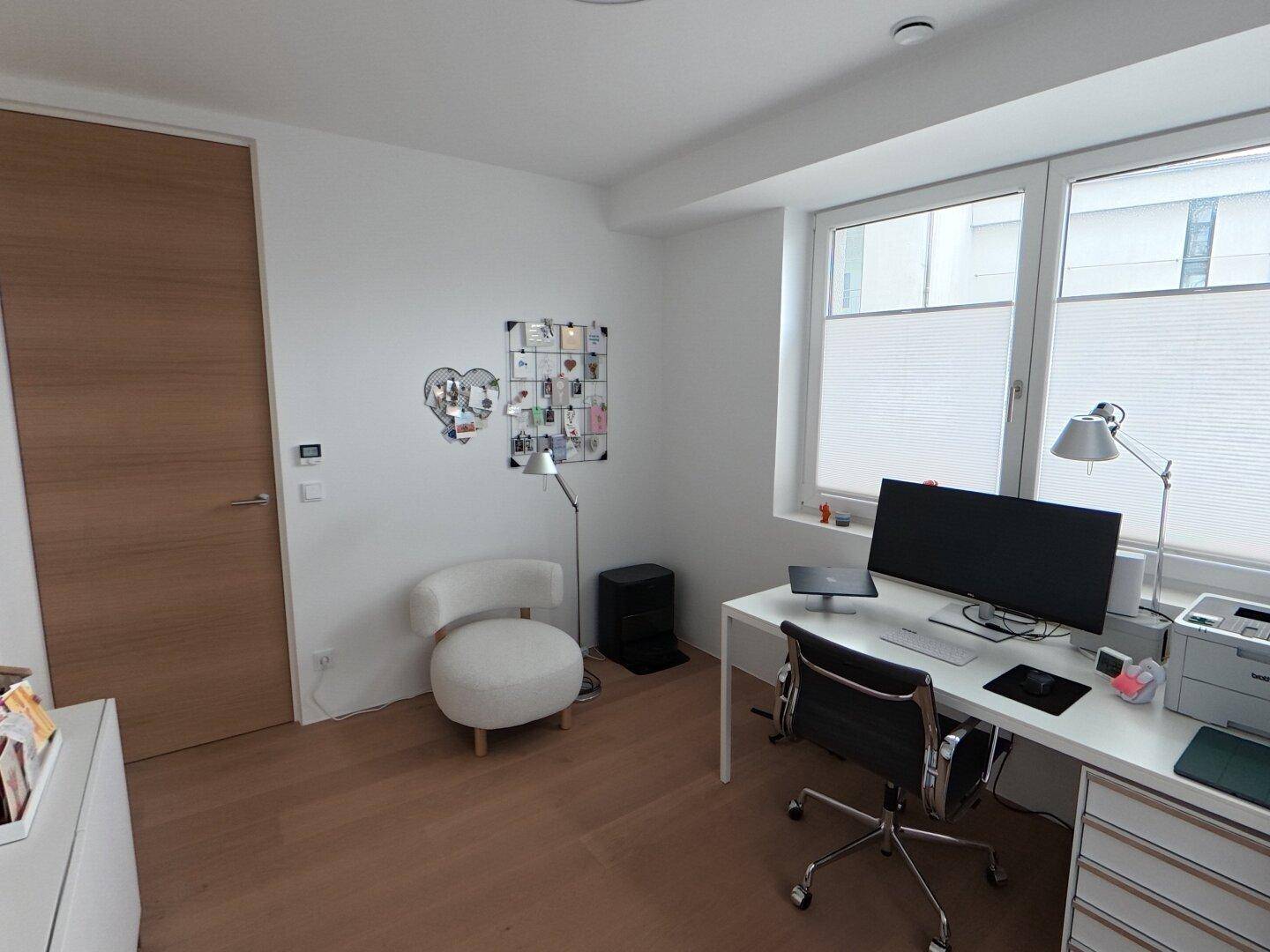 Modernes Arbeitszimmer mit Schreibtisch, weißem Stuhl und Holzboden.