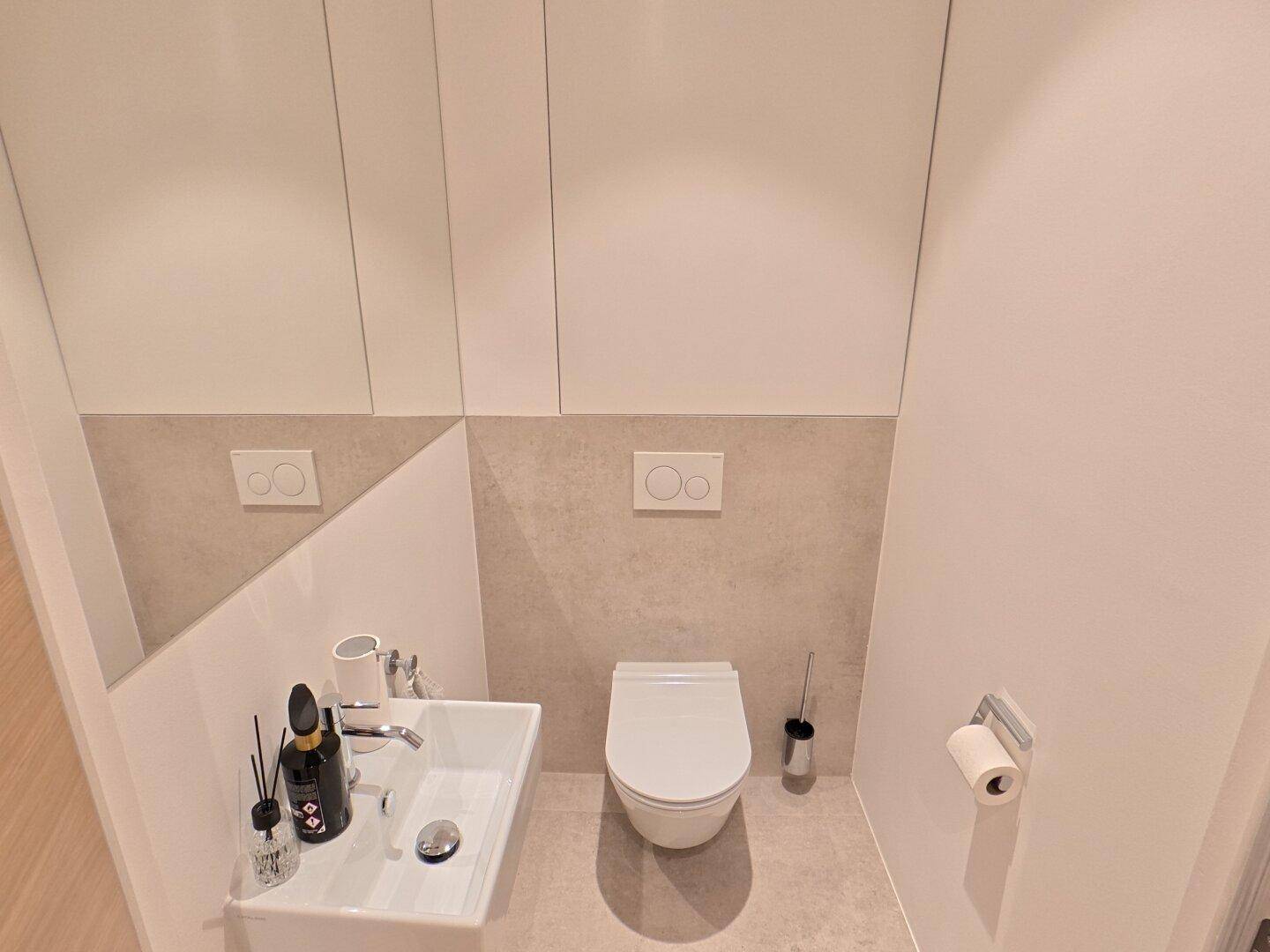 Modernes Gäste-WC mit wandhängender Toilette, kleinem Waschbecken und Spiegel.