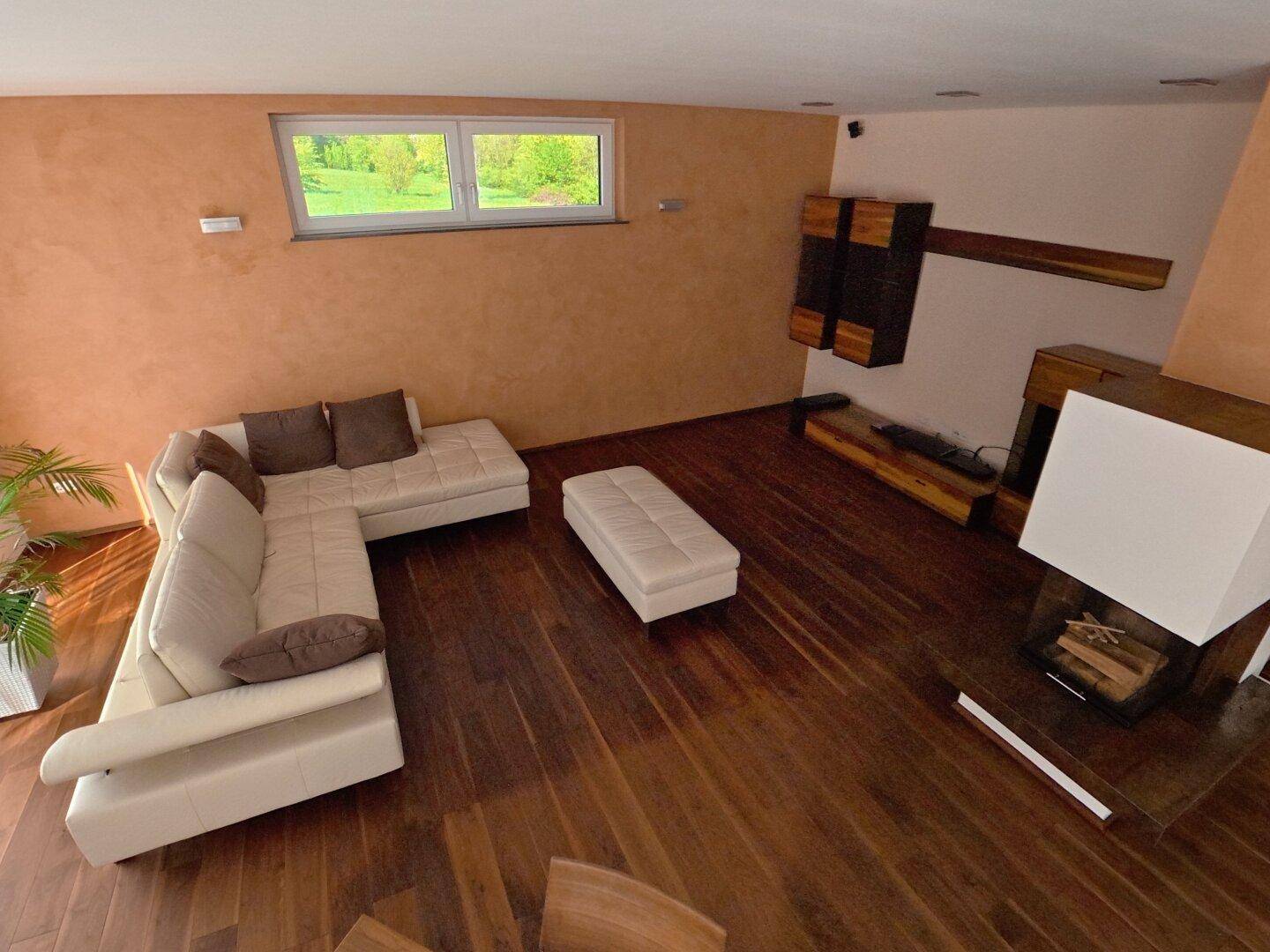 Gemütlicher Wohnbereich mit Ecksofa, modernem Kamin und Holzboden, hell beleuchtet.