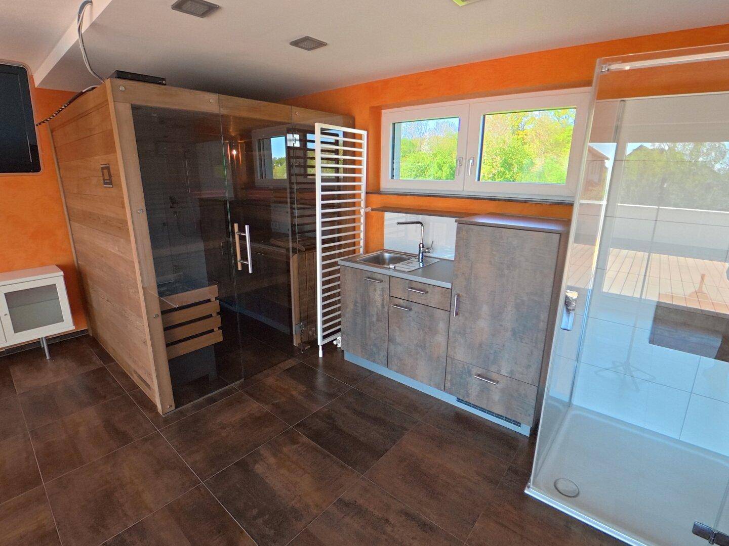 Privater Wellnessbereich mit Sauna, Dusche und kleiner Küchenzeile, ideal zur Entspannung.