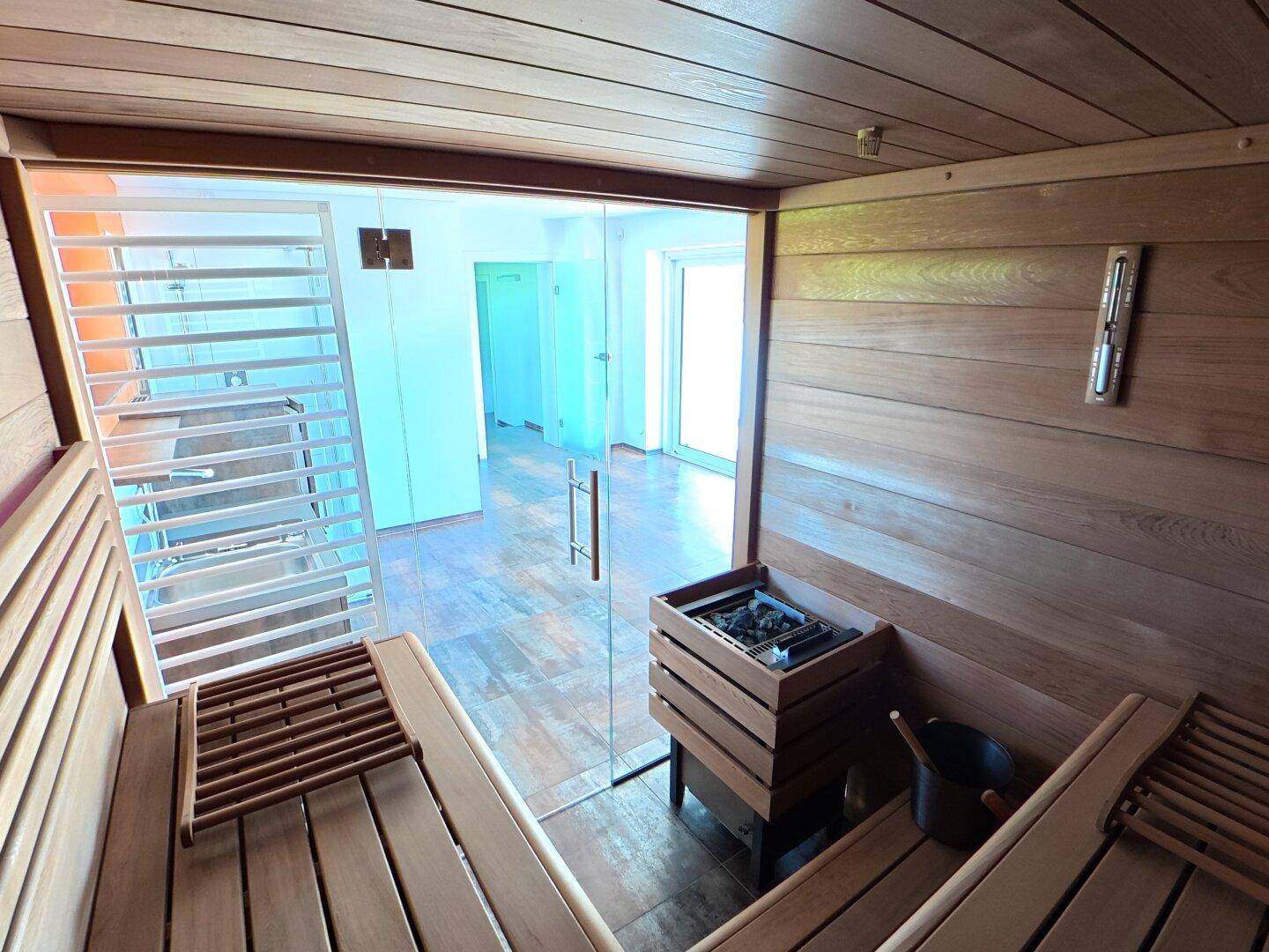 Innenansicht der modernen Holzsauna mit Bänken und Heizofen, bereit zur Nutzung.