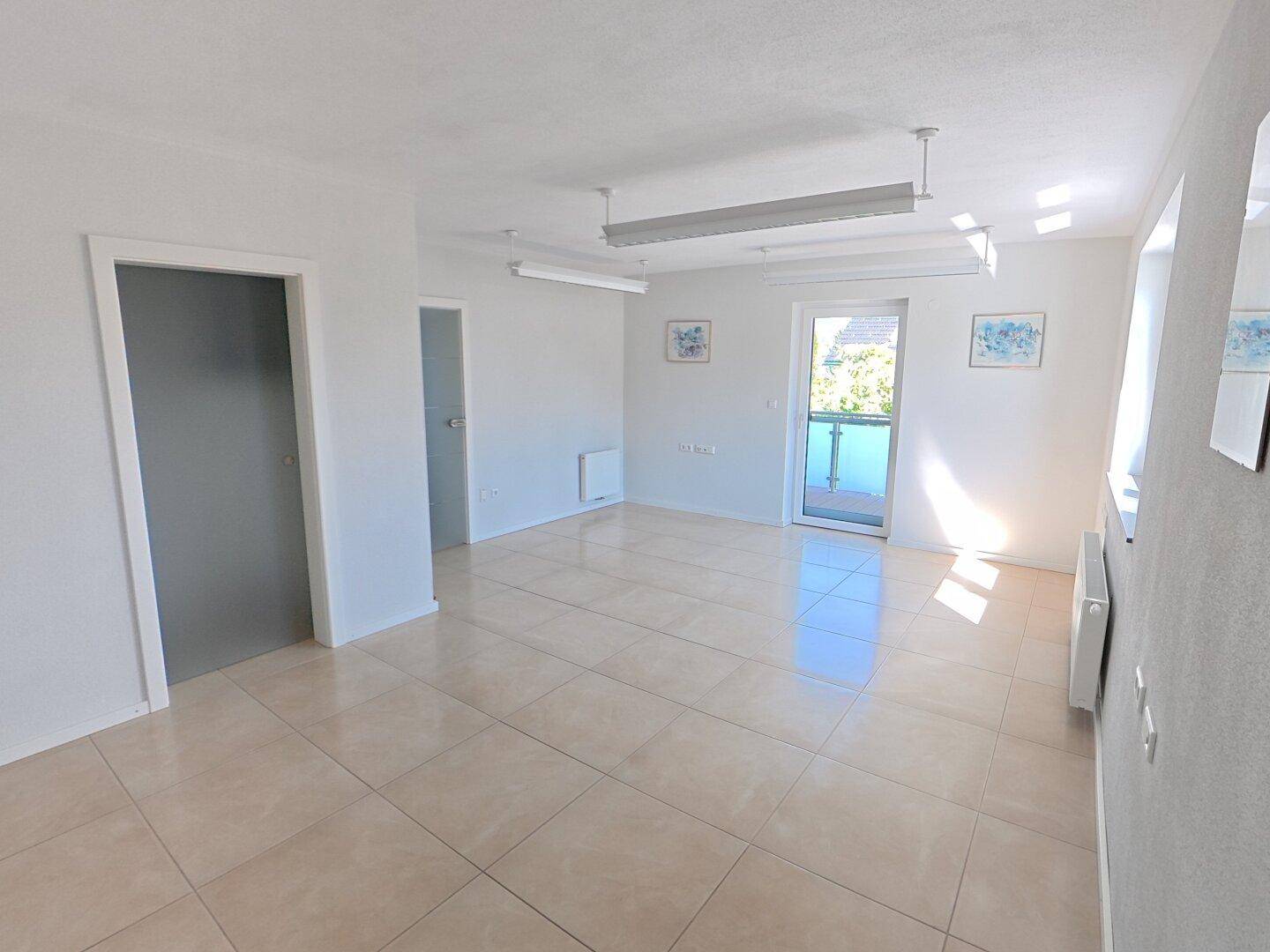 Heller, unmöblierter Raum mit Fliesenboden und Zugang zu einem französischen Balkon.