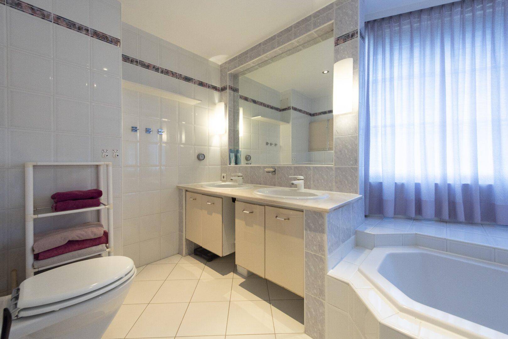 Modernes Badezimmer mit Doppelwaschbecken, Badewanne und großem Spiegel.