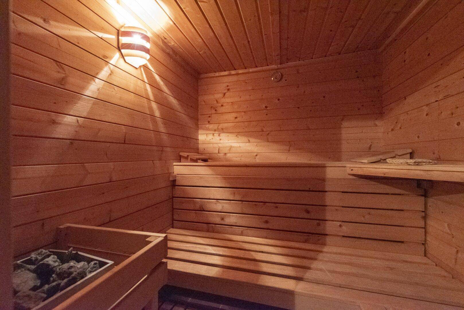 Traditionelle Holzsauna mit Bänken und Saunaofen für entspannende Momente.