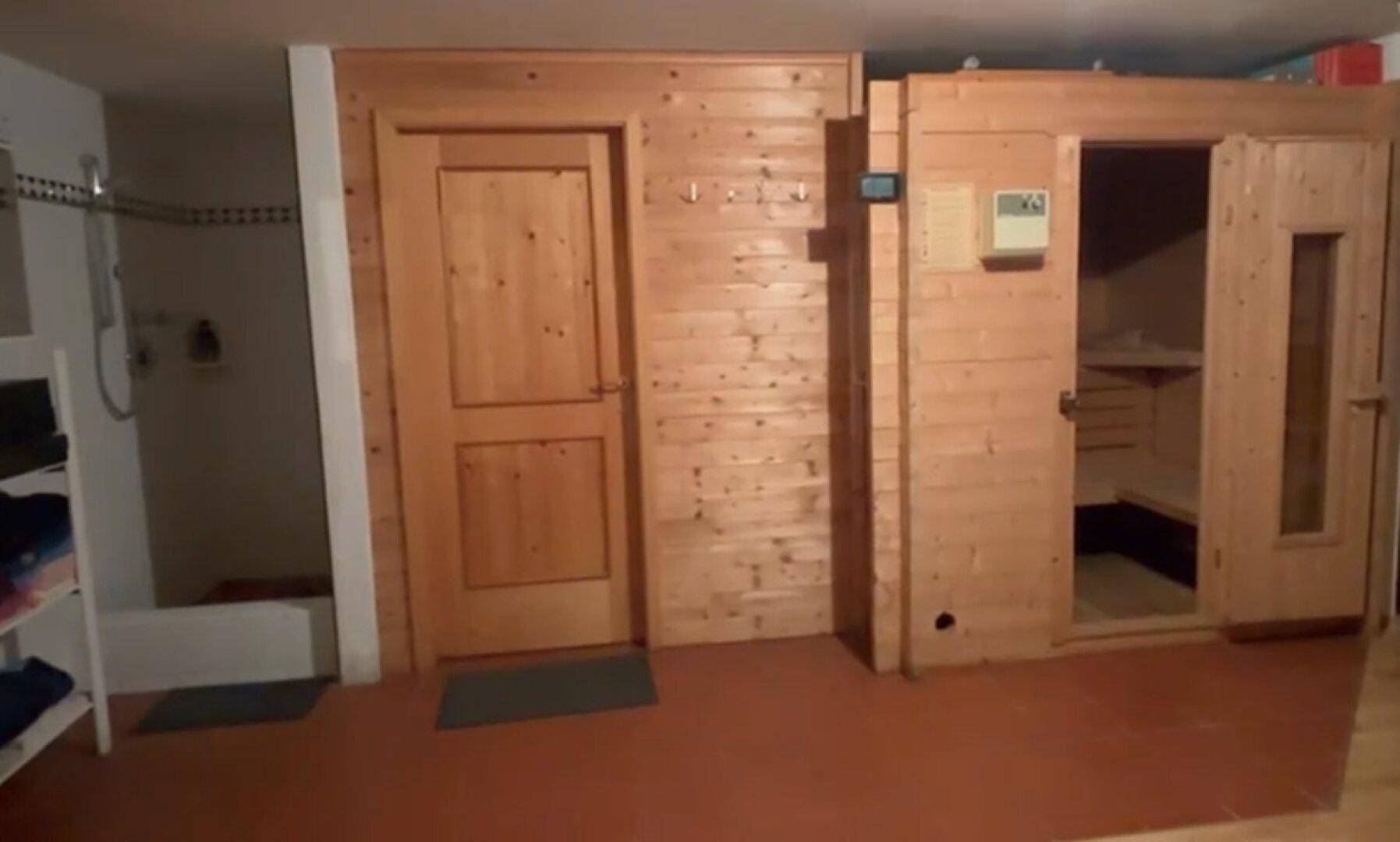 Wellnessbereich mit Sauna und angrenzender Dusche, alles in Holzoptik gehalten.