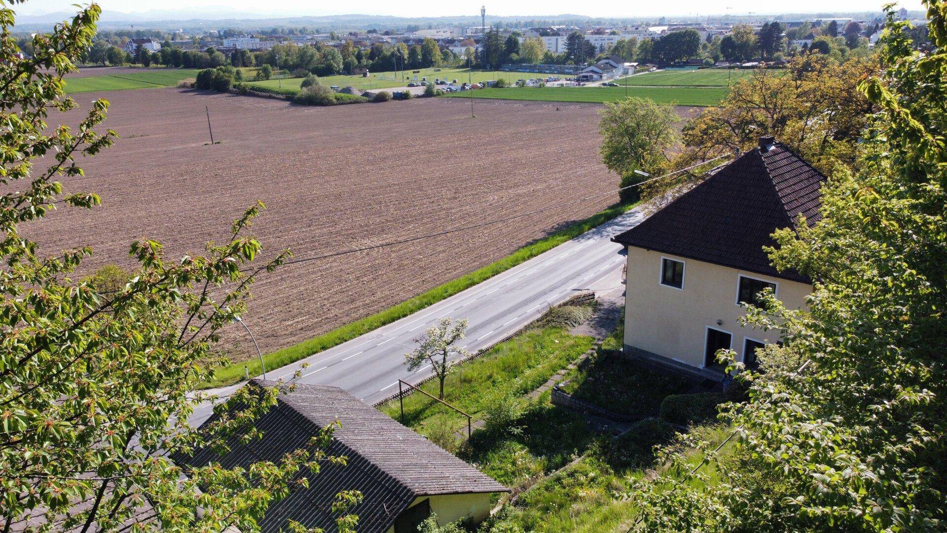 Blick von oben auf das Haus mit angrenzenden Feldern und einer Landstraße im Vordergrund.