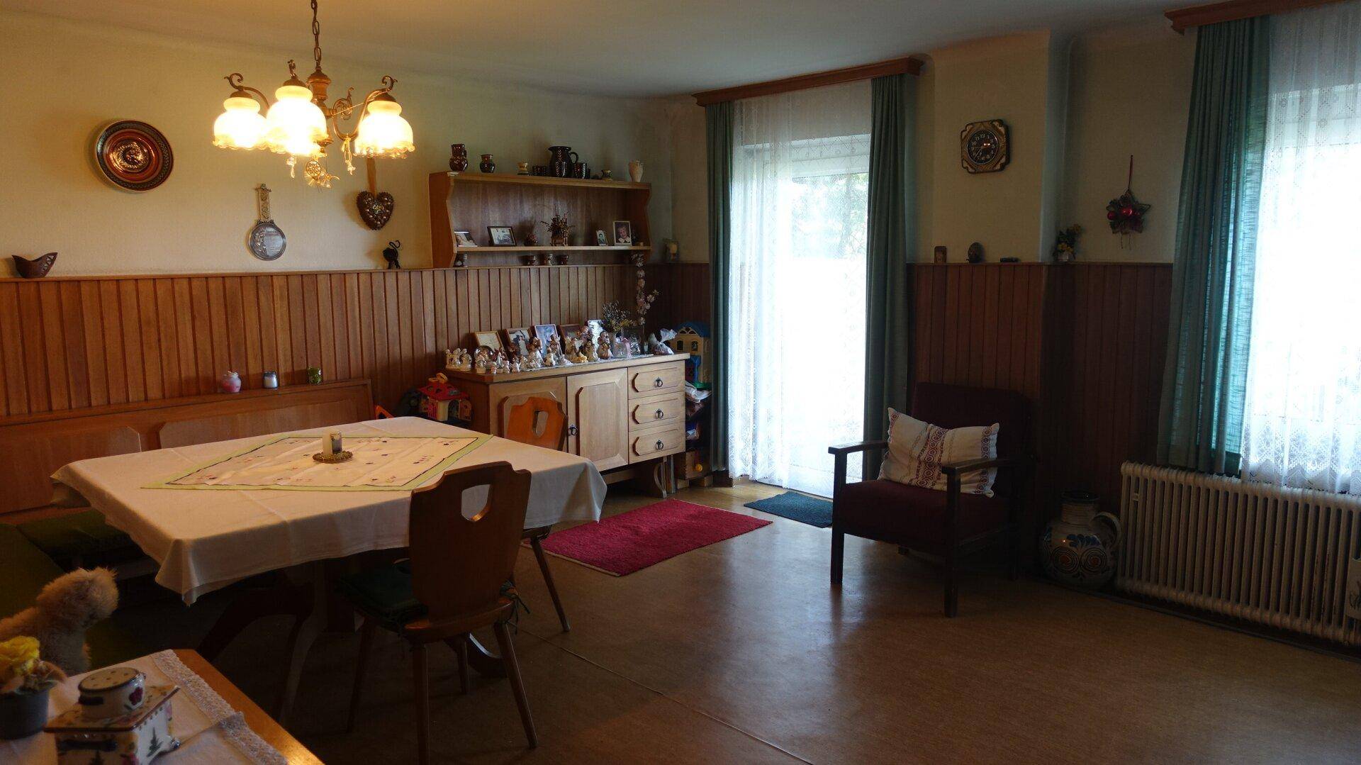Gemütlicher Wohn-Essbereich mit Holztäfelung, Esstisch und Zugang zum Außenbereich.