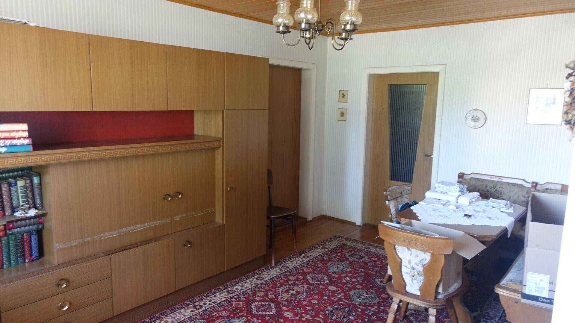 Esszimmer mit großem Holzschrank, Esstisch und Teppichboden in traditionellem Stil.