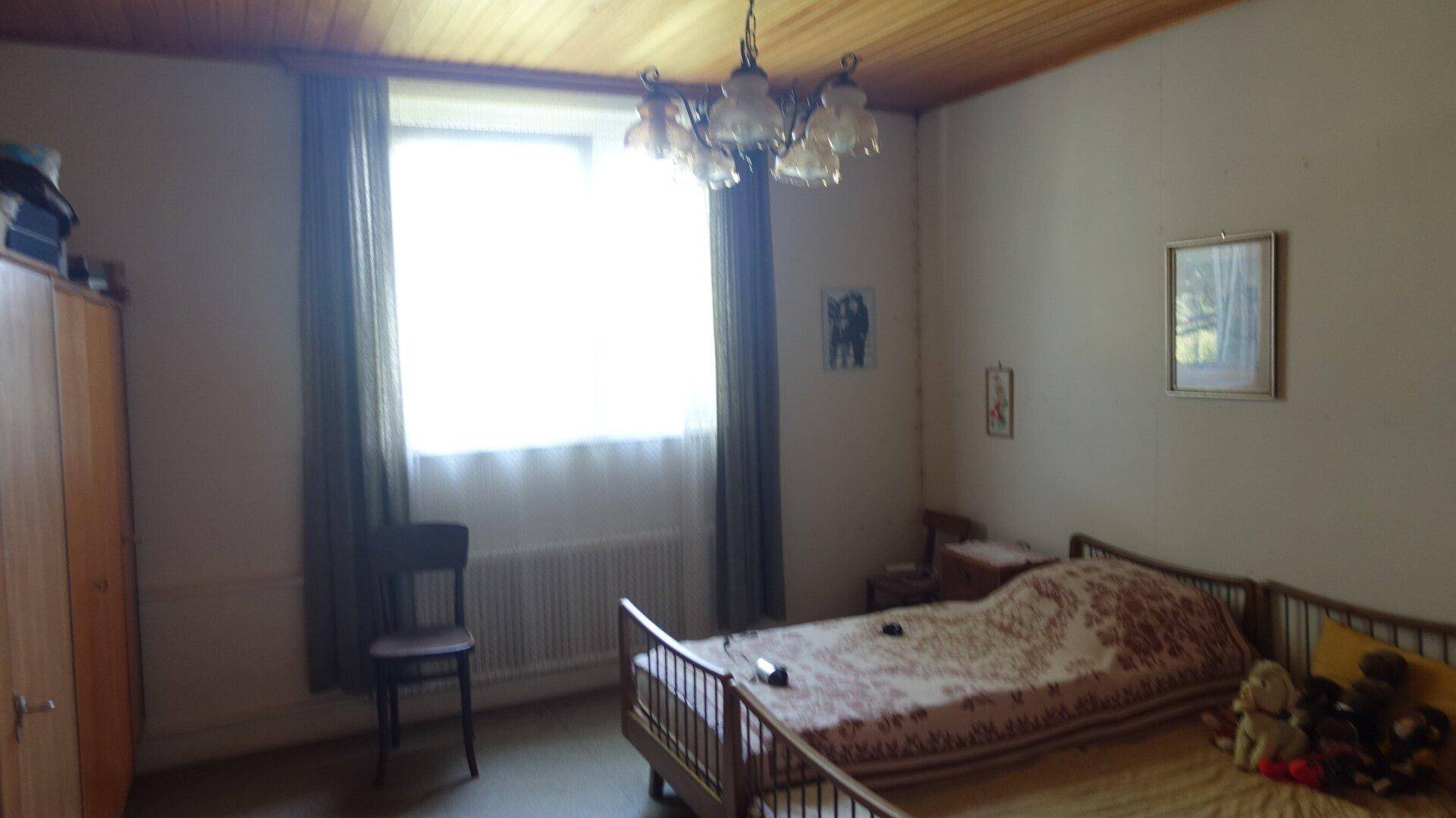 Schlafzimmer mit Holzbett, Kleiderschrank und Fenster, einfach und funktional eingerichtet.