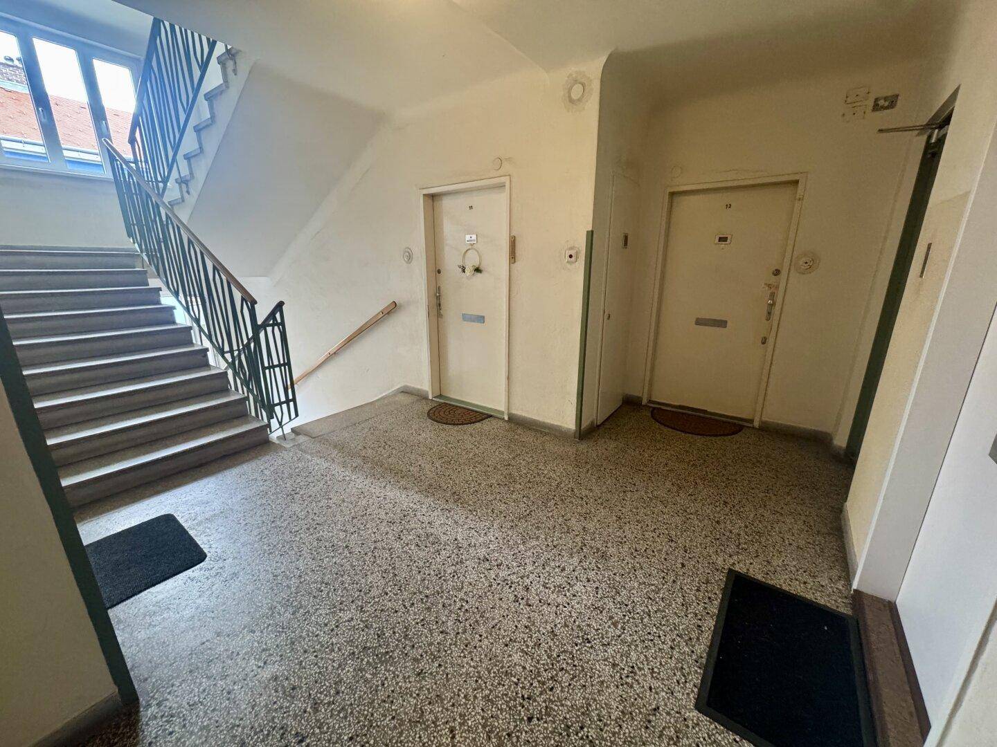 Treppenhaus und Eingangsbereich mit Terrazzoboden und Zugang zu den Wohnungen.