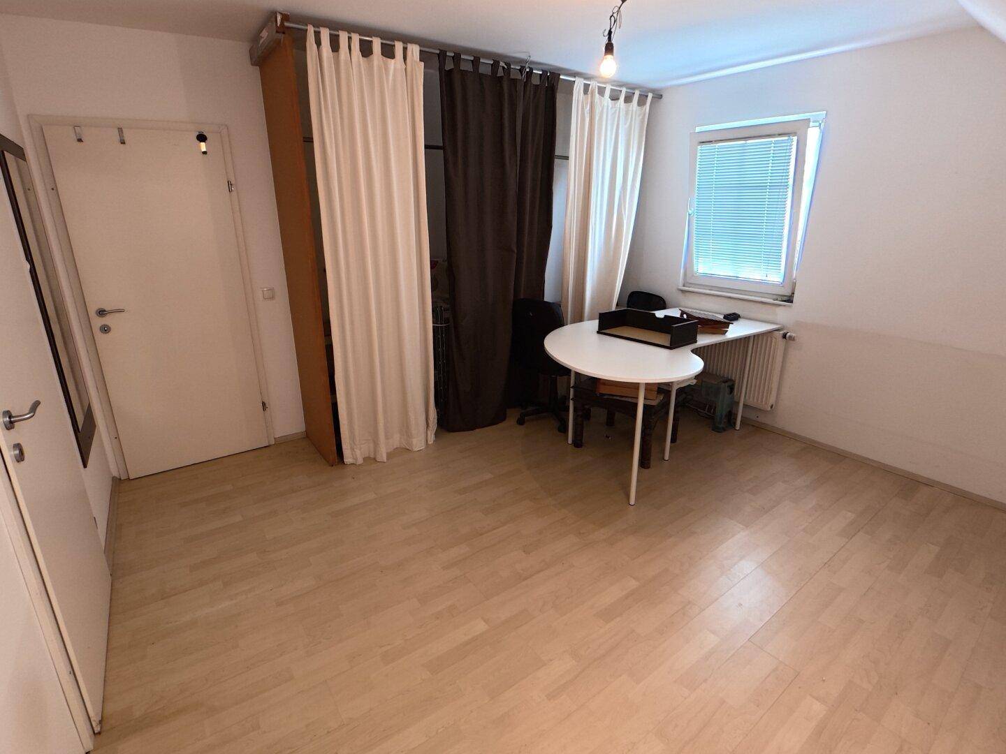 Arbeitszimmer mit Schreibtisch, Bürostuhl und Laminatboden.