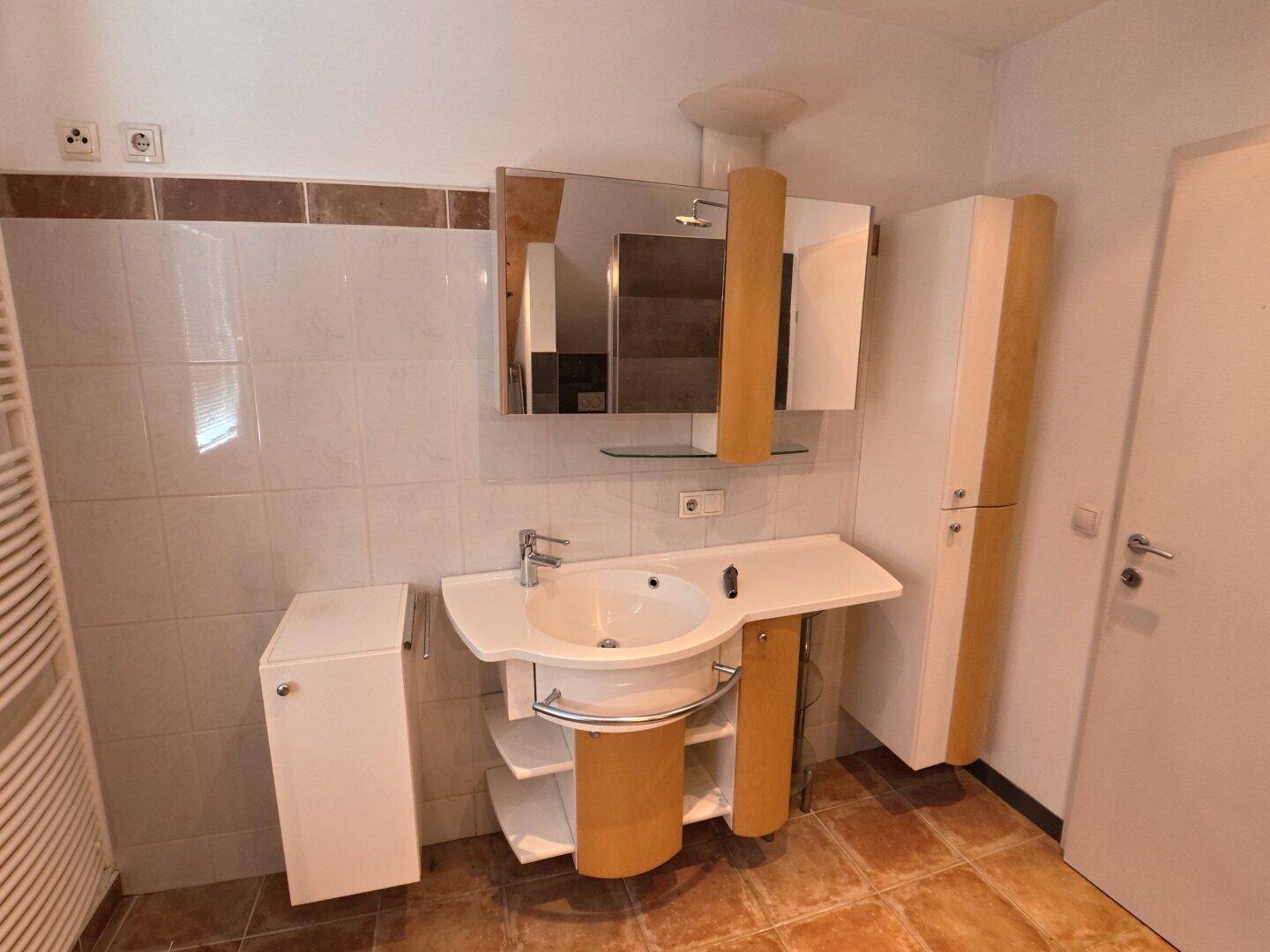 Badezimmer mit Einzelwaschbecken, Spiegelschrank und beheiztem Handtuchhalter.