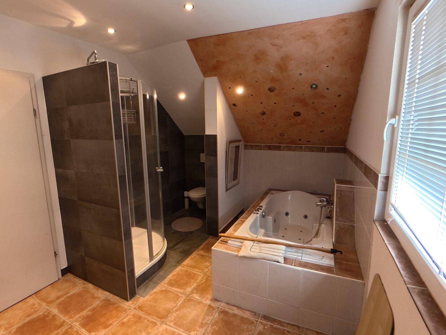 Badezimmer mit Whirlpool-Badewanne, Duschkabine und Dachschräge.