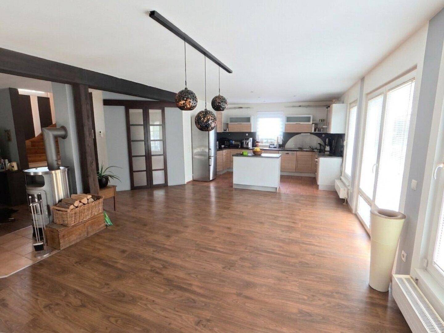 Offener Wohn-Essbereich mit Laminatboden, Kaminofen und integrierter Küche.
