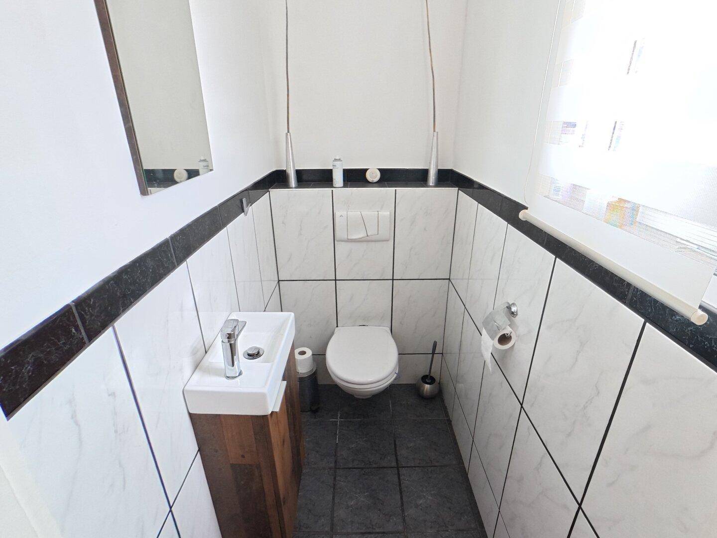 Kleines Gäste-WC mit modern gefliesten Wänden und Waschbecken.