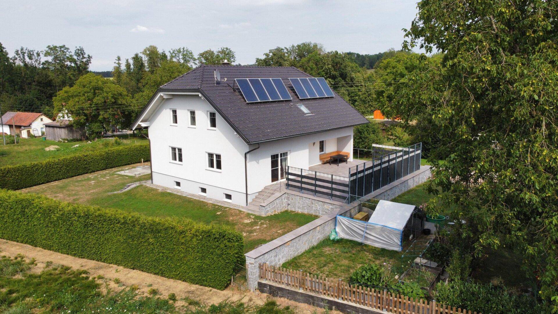 Luftaufnahme des Hauses mit großer Terrasse und Solaranlage auf dem Dach, umgeben von Natur.