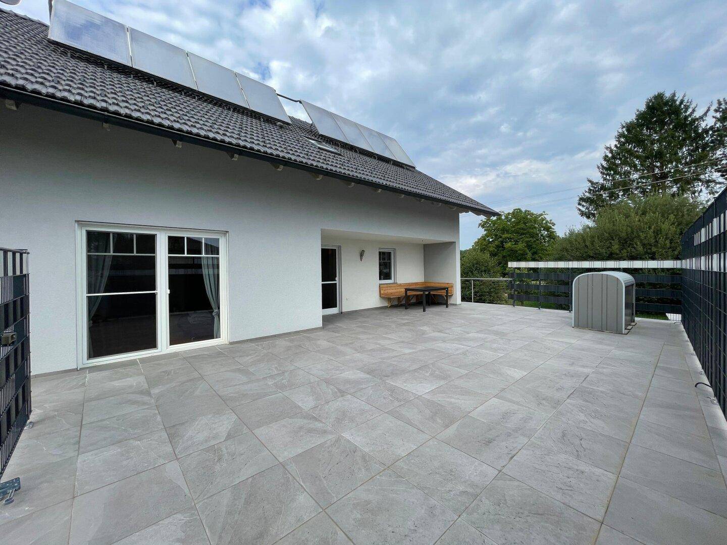 Geräumige, geflieste Terrasse mit viel Platz für Gartenmöbel und Zugang zum Haus.
