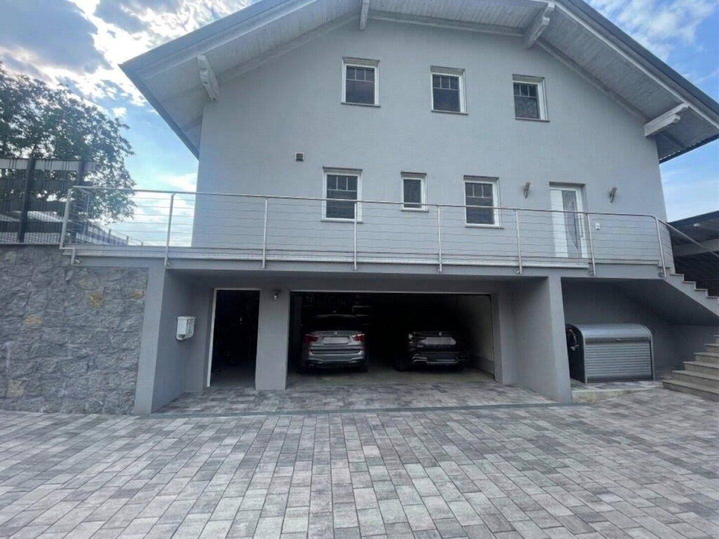 Vorderansicht des Hauses mit Doppelgarage und gepflasterter Zufahrt.