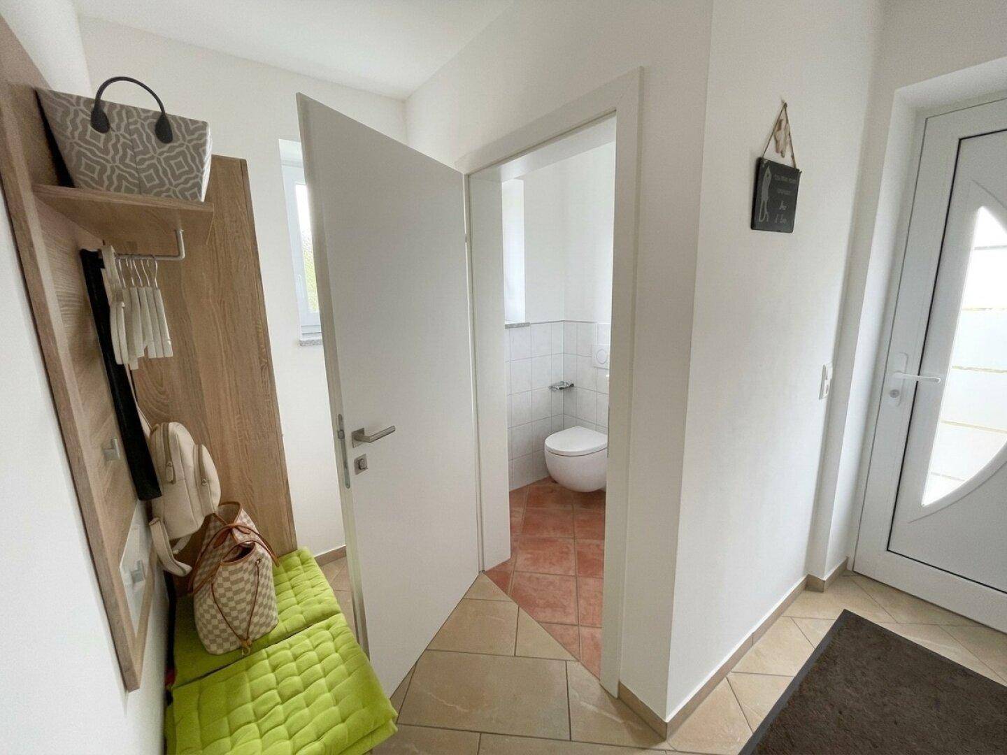 Separate Gästetoilette mit WC und Fliesenboden, direkt vom Flur zugänglich.