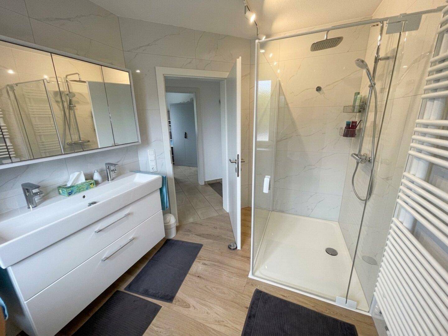 Modernes Badezimmer mit großer begehbarer Dusche, Doppelwaschbecken und Handtuchheizkörper.