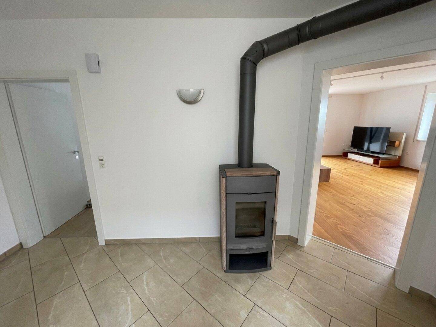 Heller Flur mit modernem Holzofen und Zugang zu weiteren Räumen.