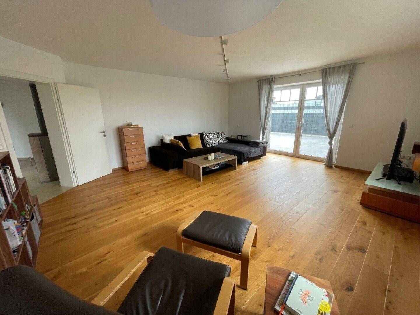 Helles Wohnzimmer mit gemütlicher Sitzecke, Holzboden und direktem Zugang zur Terrasse.