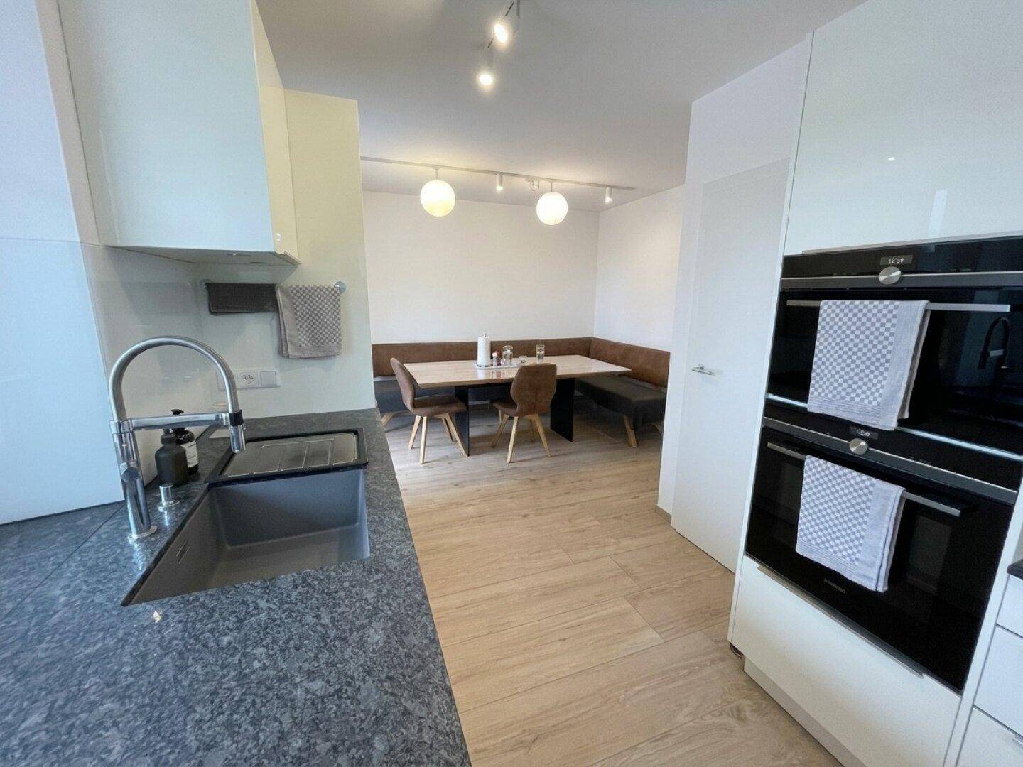 Essbereich in der Küche mit Eckbank, Holztisch und modernen Leuchten.