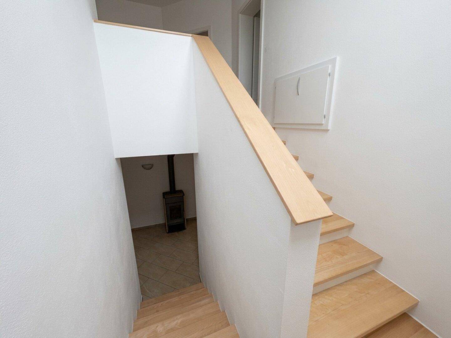 Holztreppe führt in den Kellerbereich mit sichtbarem Ofen.