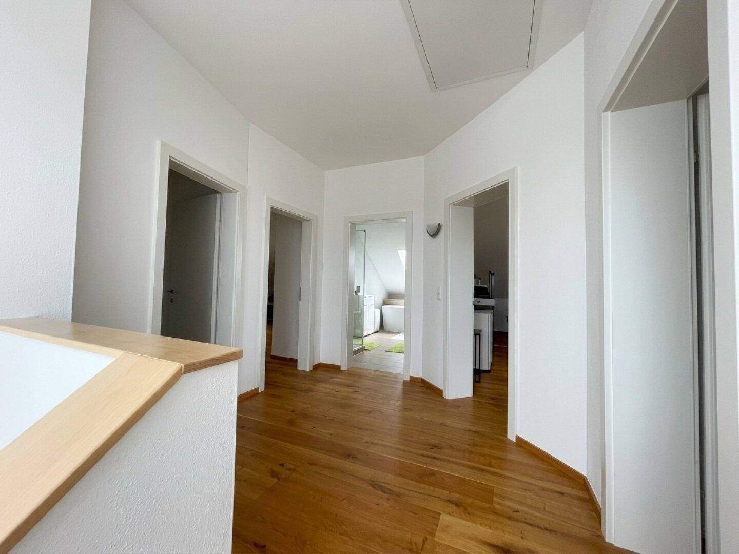 Heller Flur im Obergeschoss mit Holzboden und Zugang zu mehreren Zimmern.