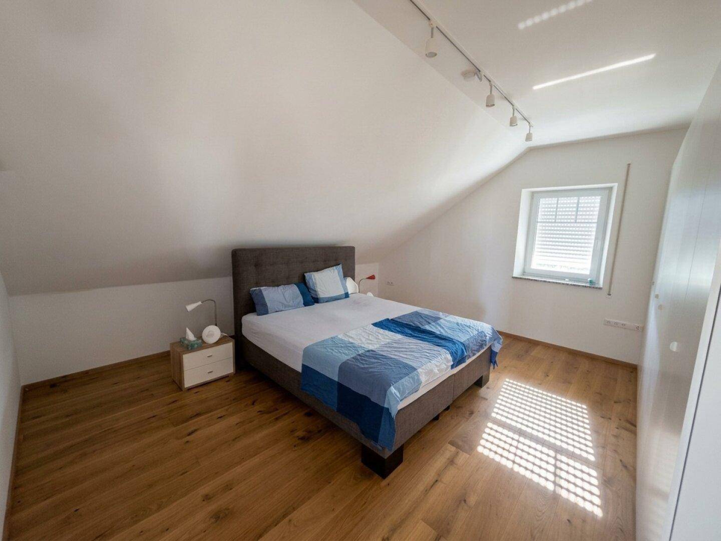 Gemütliches Schlafzimmer im Dachgeschoss mit Holzboden und schrägen Wänden.