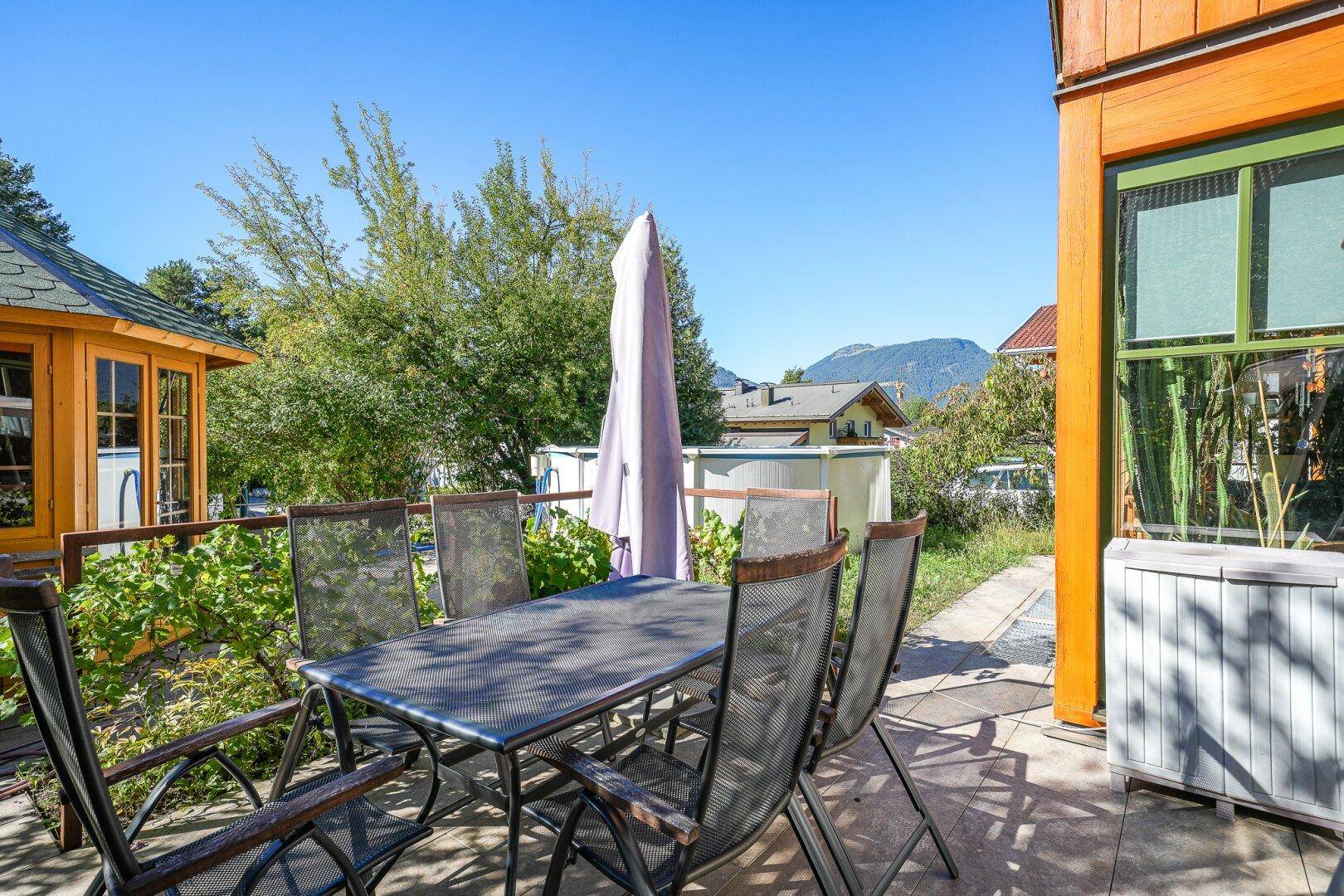 Gemütliche Terrasse mit Gartenmöbeln und Blick ins Grüne an einem sonnigen Tag.