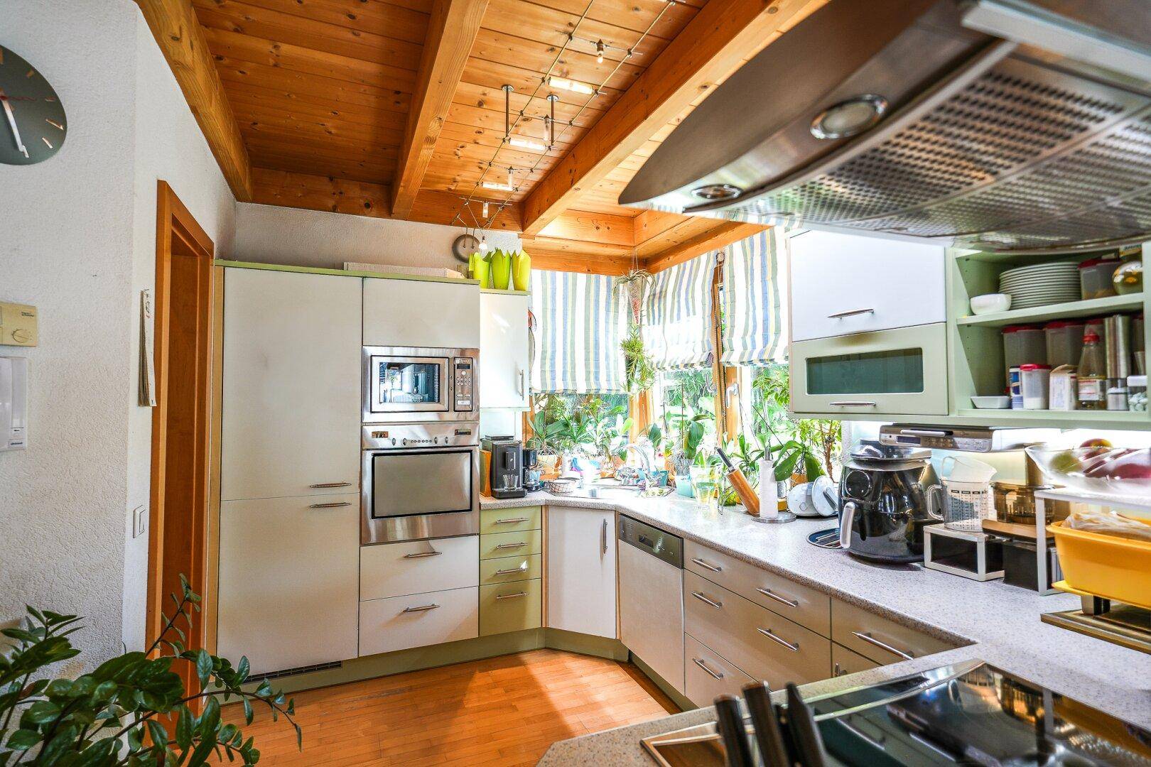 Funktionale Küche mit Holzbalkendecke, Einbaugeräten und Blick in den Garten.