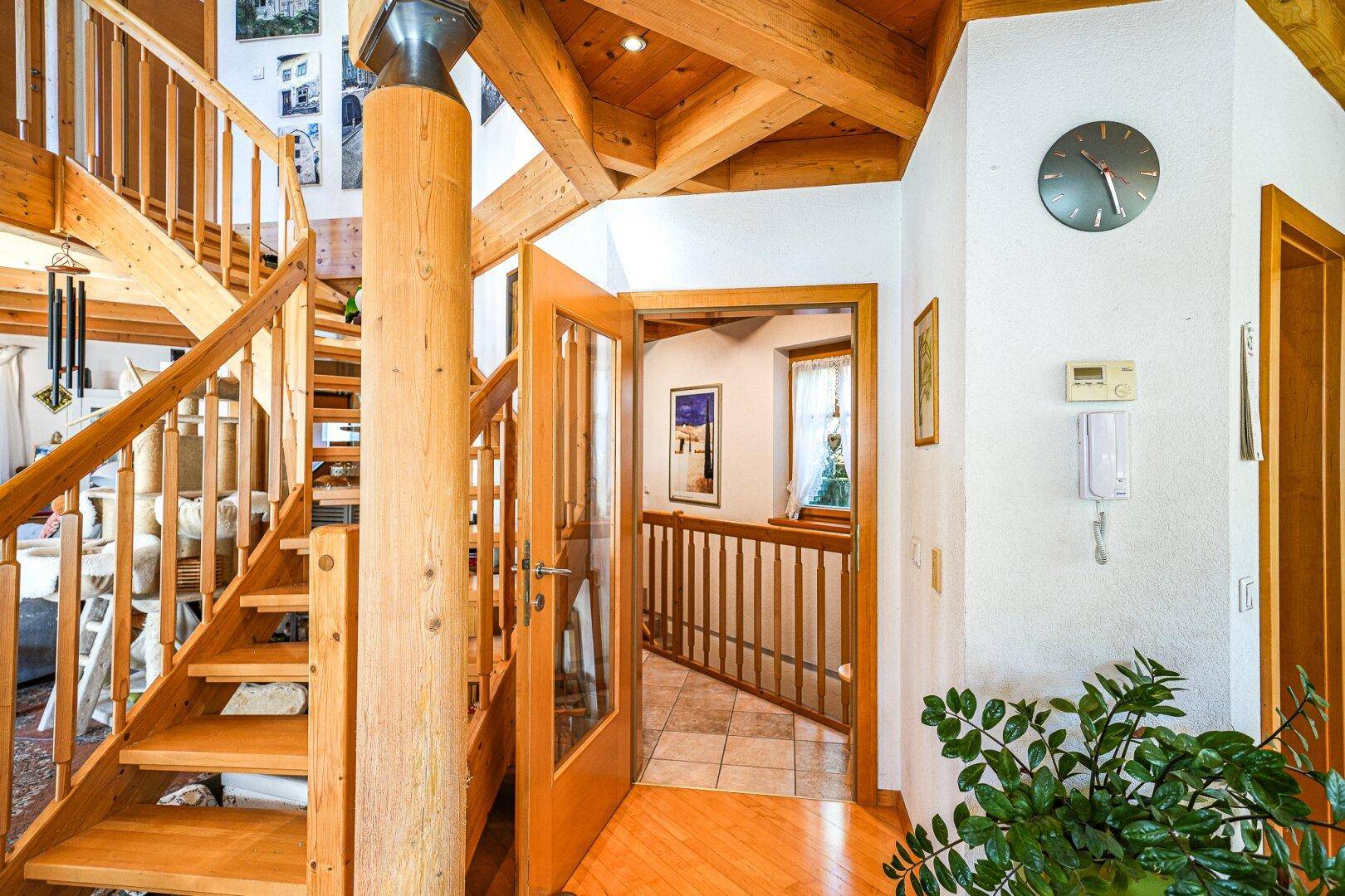 Heller Flur mit Holztreppe und Holzbalkendecke, der zu den oberen Etagen führt.