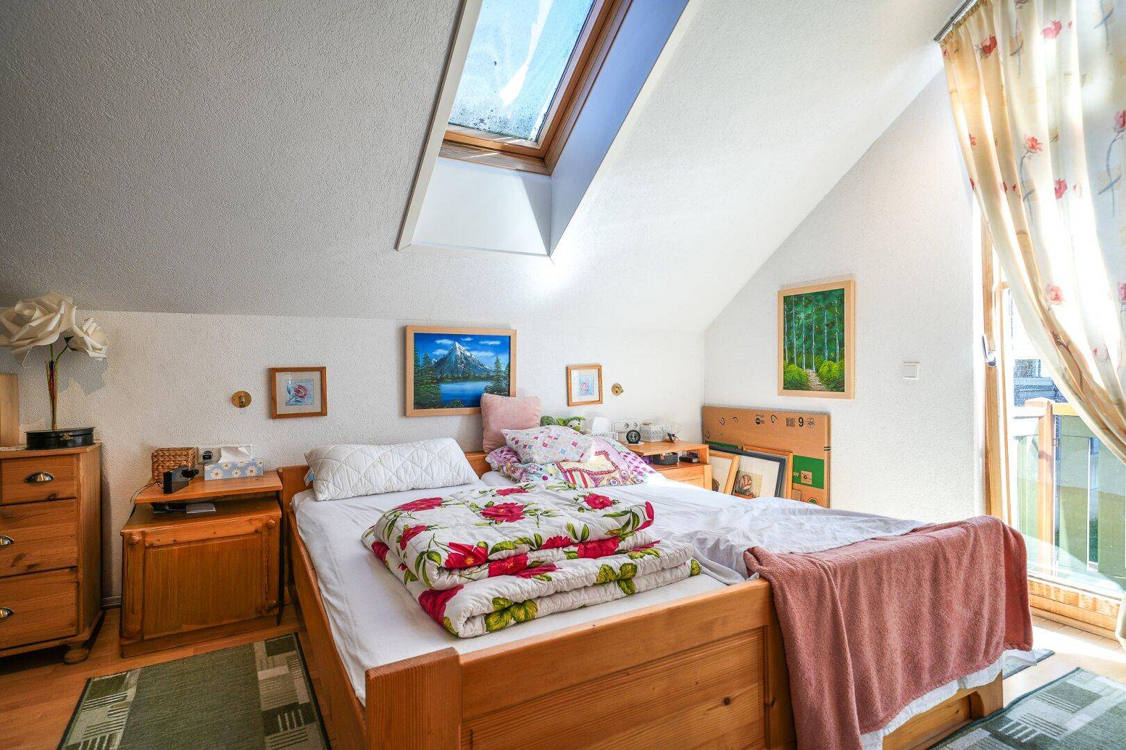Gemütliches Schlafzimmer mit Holzbett, Dachschräge und Dachfenster für viel Licht.